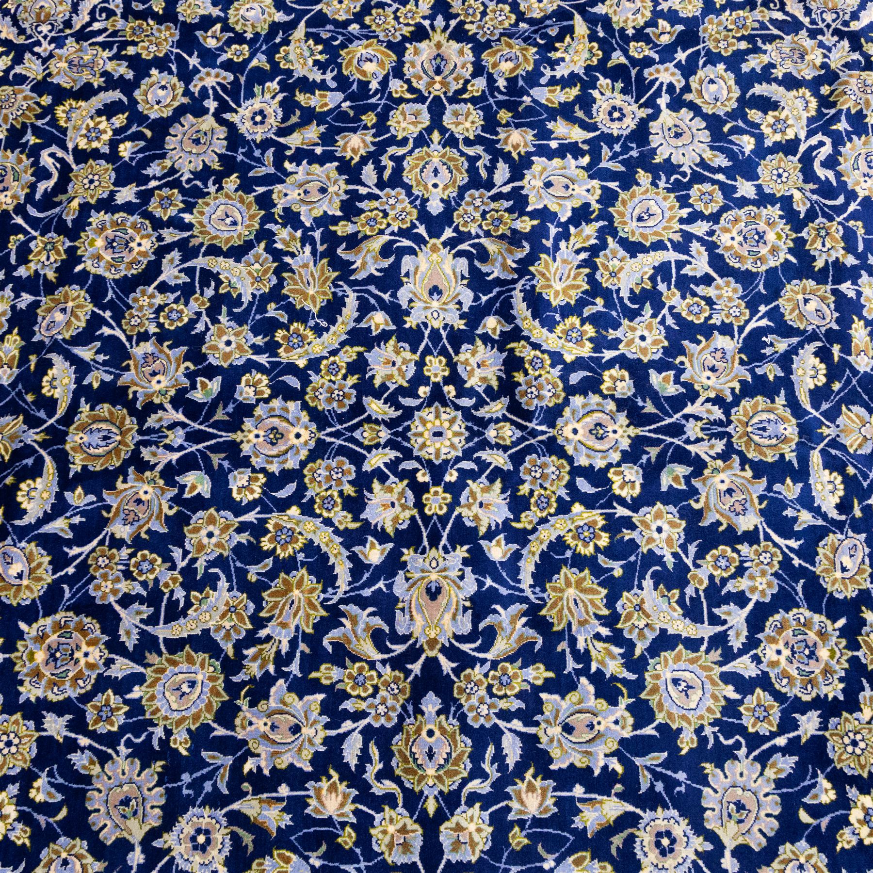 Central Persian Kashan hand-knotted carpet, deep indigo blue field densely decorated with all-over vine, palmette and flowering sprays arranged in a symmetrical pattern enclosed by broad navy border of stylized palmettes, and foliate vine decoration between multiple guard stripes, with cotton fringe ends 