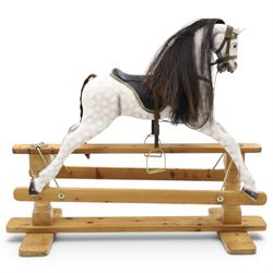Late 20th century polychrome painted rocking horse, modelled in dapple grey finish with horse hair mane and tail, leather tack and saddle, stirrups, raised on a pine trestle base