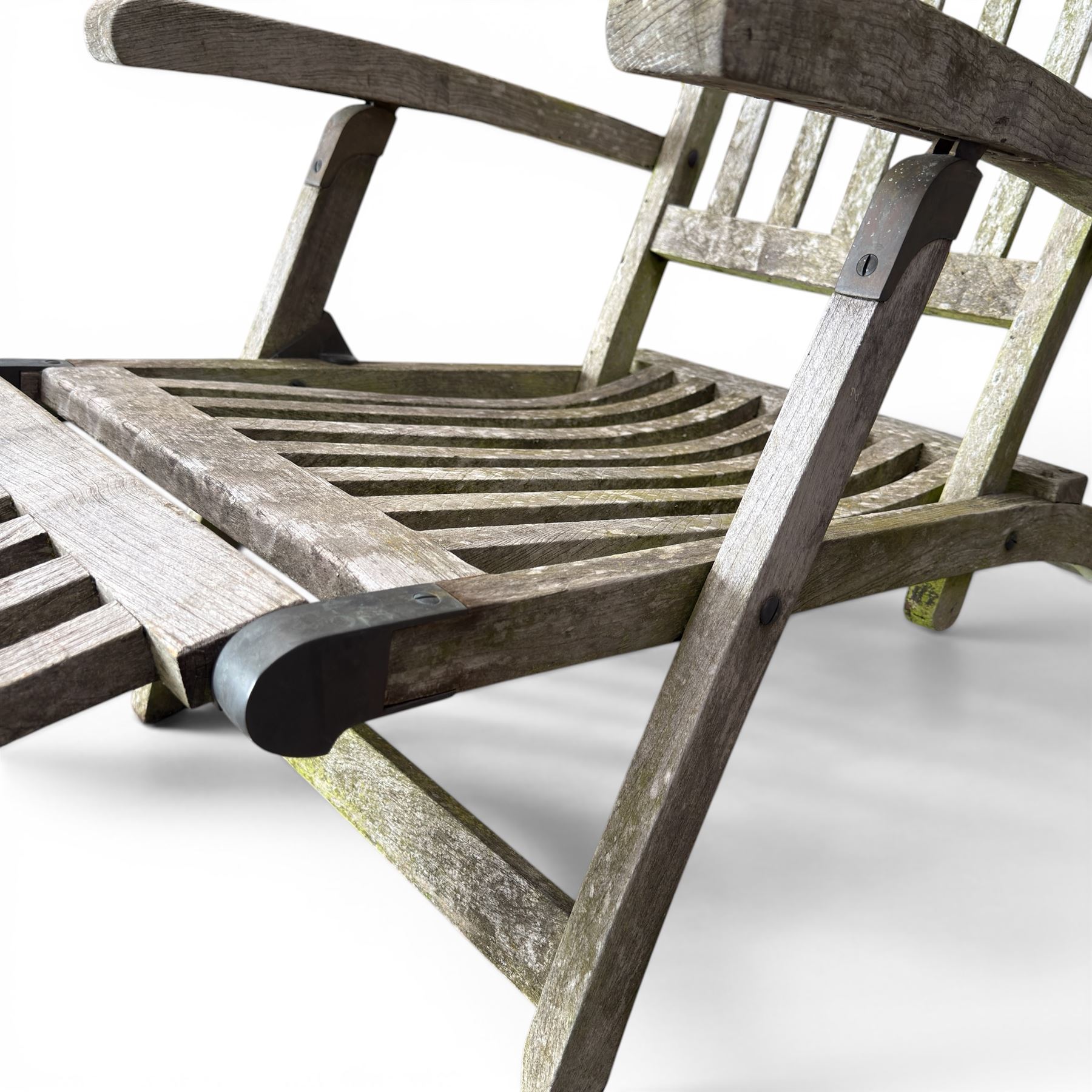 Pair of teak reclining garden steamer armchairs, each with an adjustable slatted back, curved slatted seat and footstool