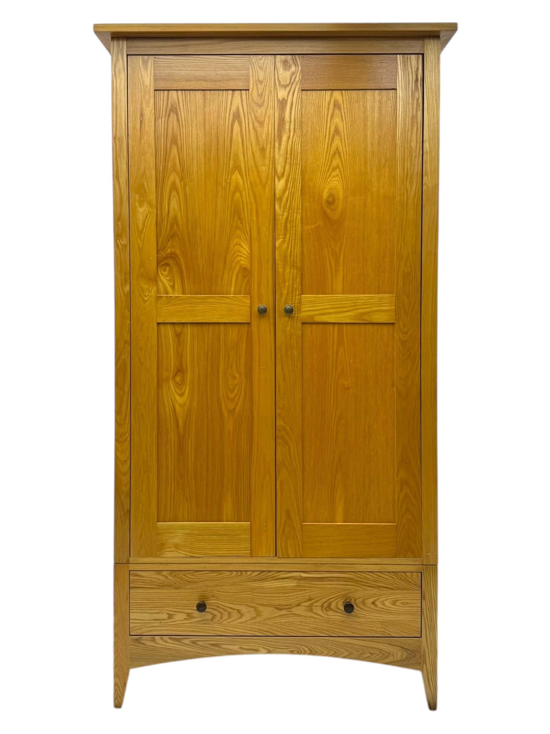 Contemporary light oak double wardrobe, projecting cornice over two panelled doors enclosing hanging rail and shelf, above full-width drawer, on shaped stile supports