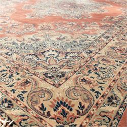 Persian Kashan rug, the rich terracotta field with central floral medallion and palmette spandrels, surrounded by a cream border of stylised boteh and foliate decoration