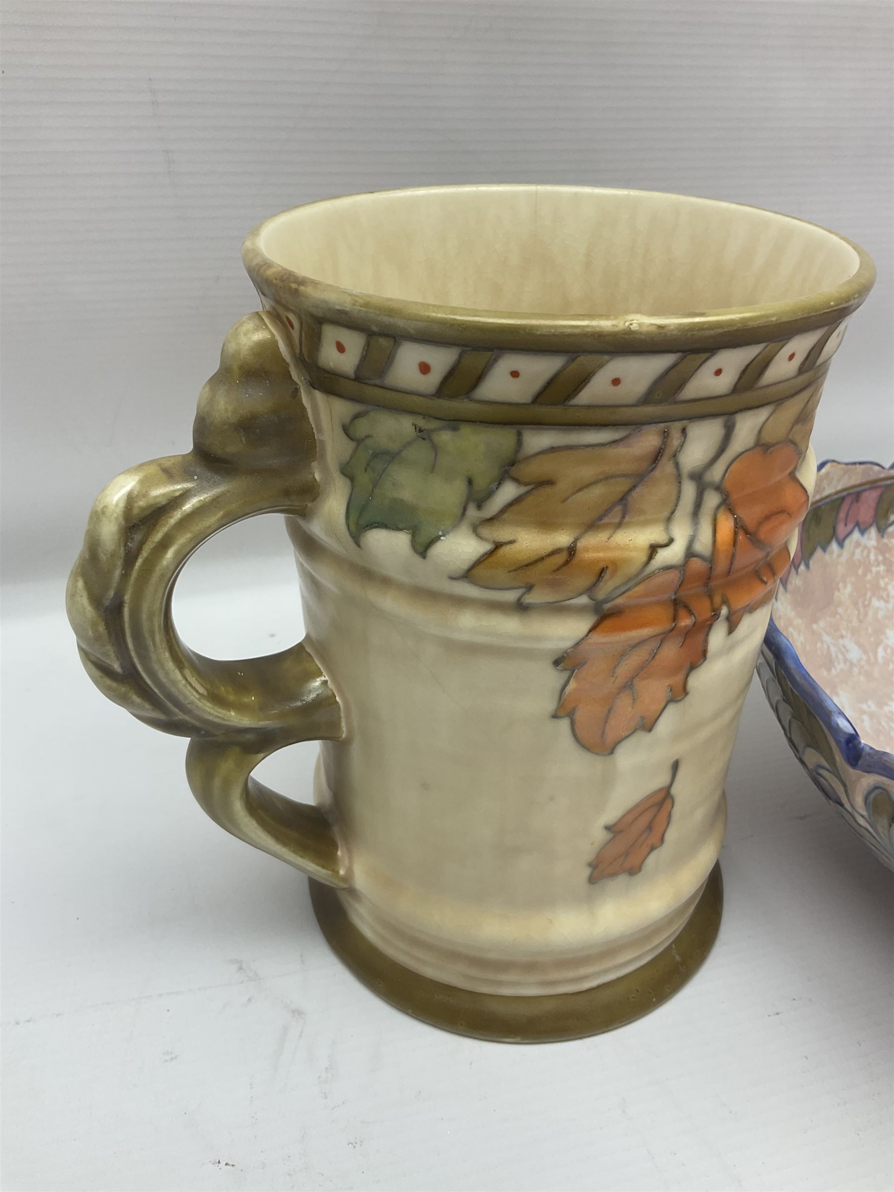 Charlotte Rhead for Crown Ducal ceramics, comprising coffin shaped vase depicting a woman in 1920s dress, a vase with handle, decorated with autumn leaves and a bowl, decorated with flowers and berries, with printed and signed marks beneath, coffin vase H24cm