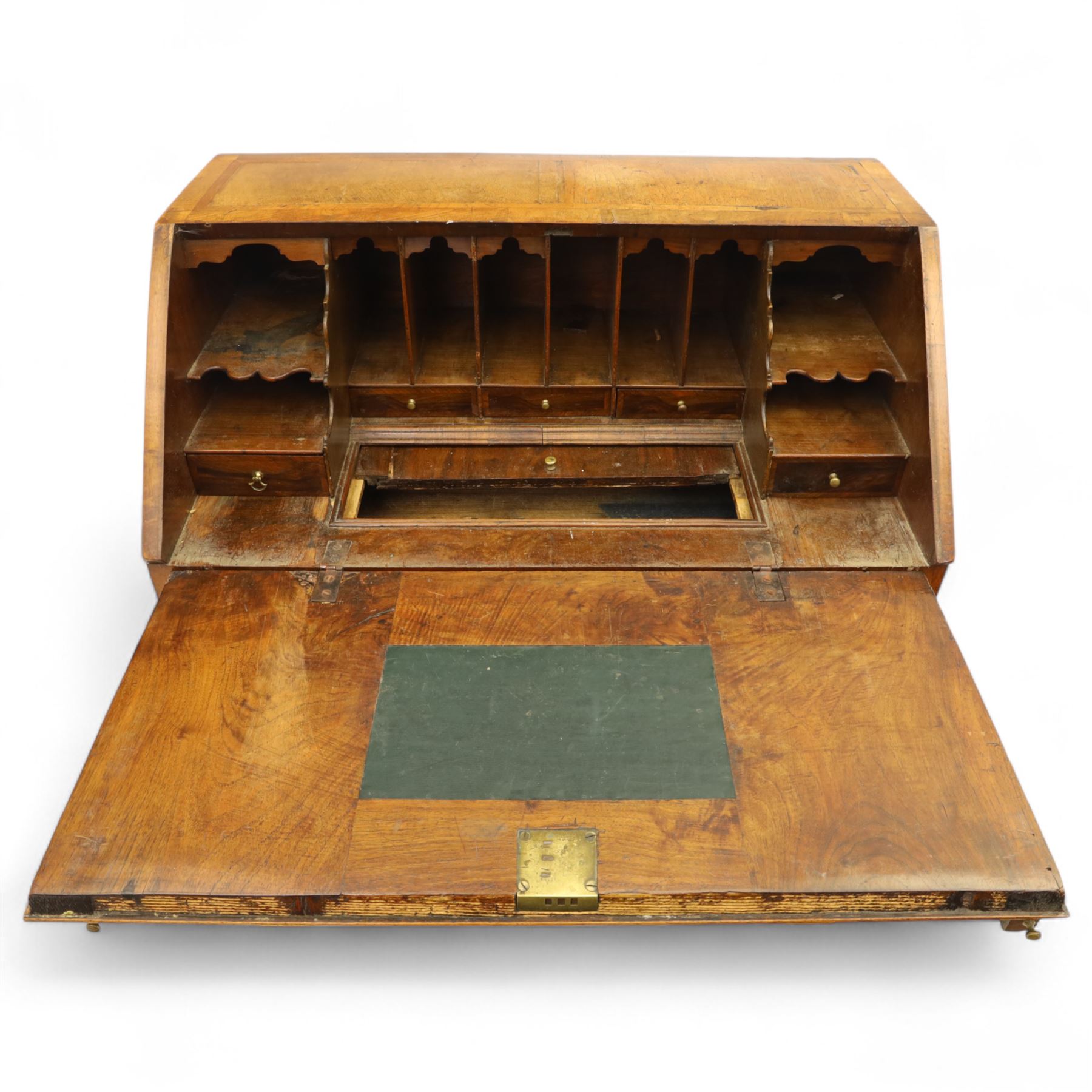 18th century walnut and herringbone banded bureau, the fall front enclosing a stepped and arched interior fitted with pigeonholes, drawers and concealed compartments, green tooled leather writing surface, over two short and three long graduated drawers with brass escutcheons and bail handles, shaped bracket feet