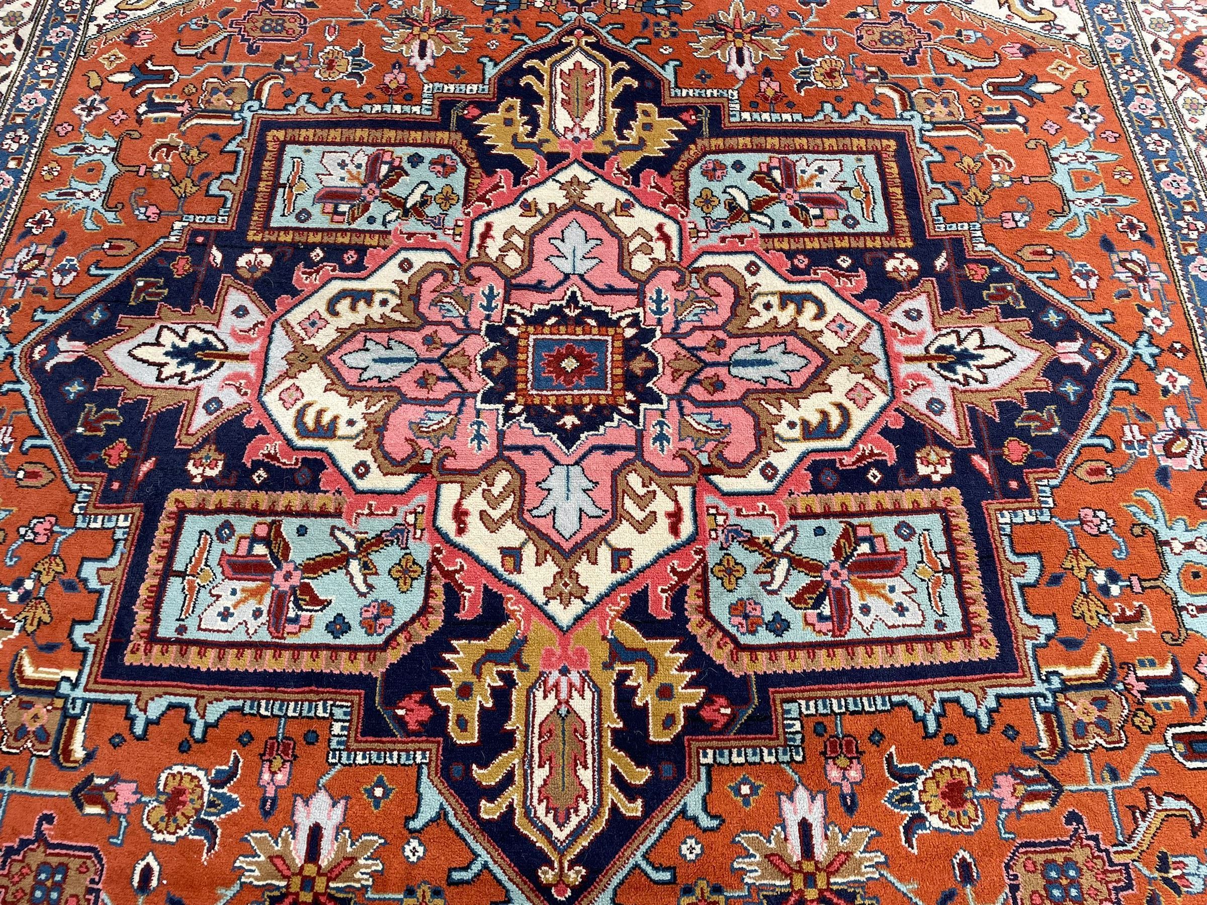 Large Persian carpet, the geometric and stylised floral medallion on rust ground field decorated with stylised plant motifs, guarded ivory border with repeating pattern
