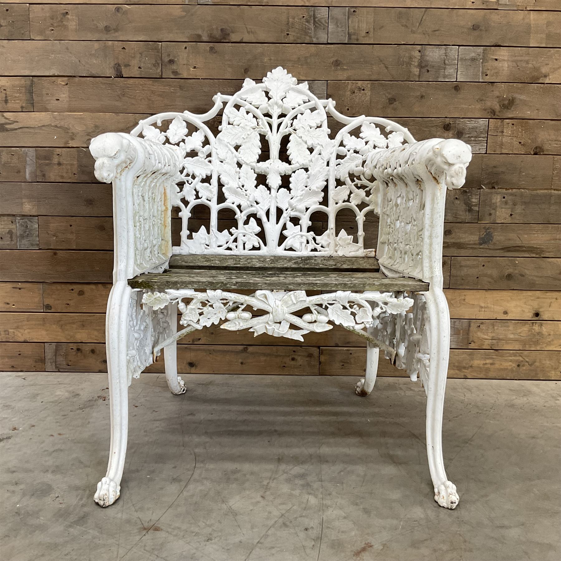 20th century Coalbrookdale design cast iron oak leaf and acorn armchair, white painted cast iron frame with slatted wooden seat, the pierced and shaped back decorated with scrolling oak branches and leafage, flanked by dog mask arm terminals over cabriole supports with paw feet