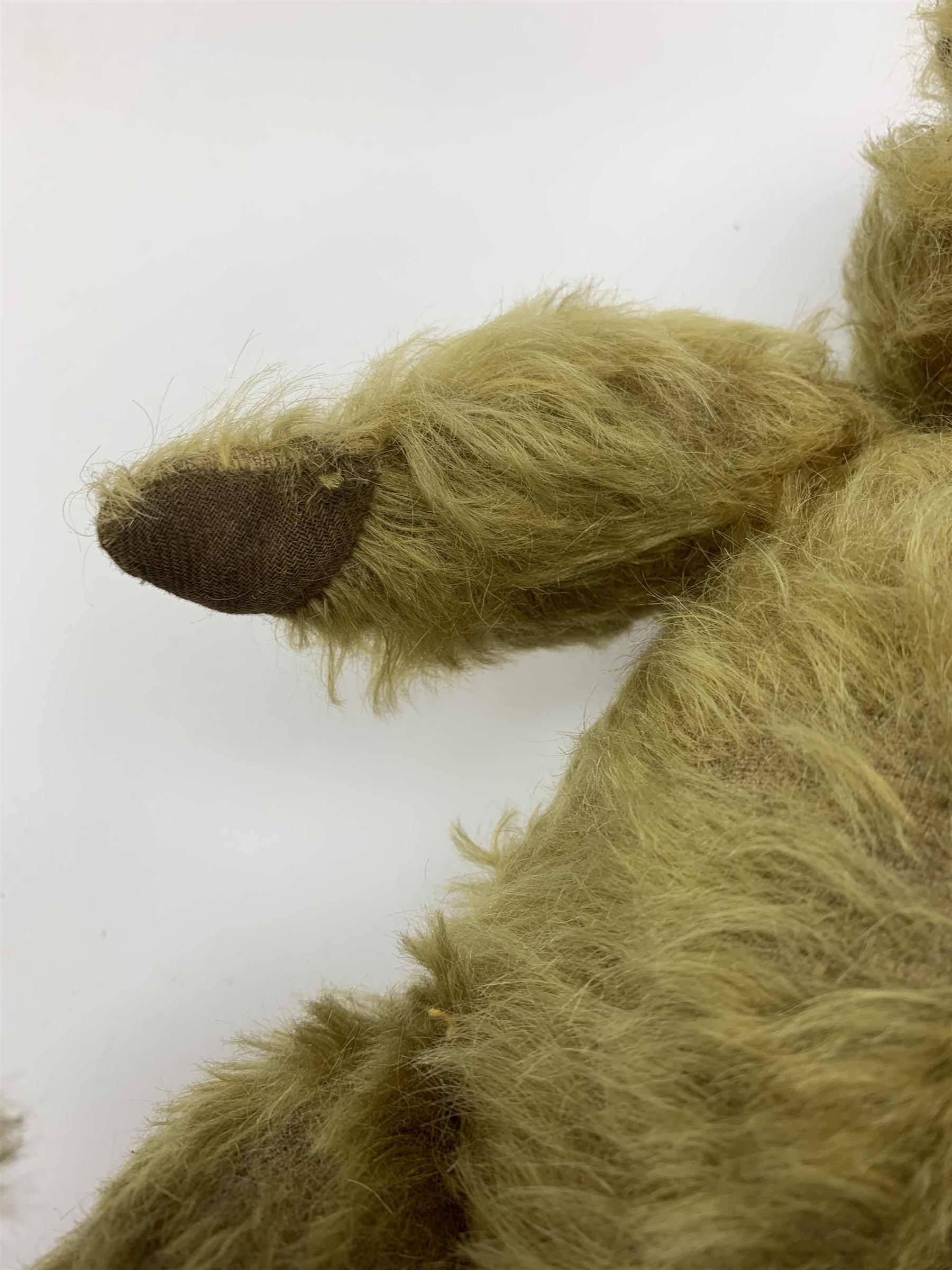 Early 20th century English teddy bear, WW1 period, with wood wool filled mohair body, fixed head with one boot button eye and vertically stitched nose and mouth and jointed limbs with cloth paw pads H16