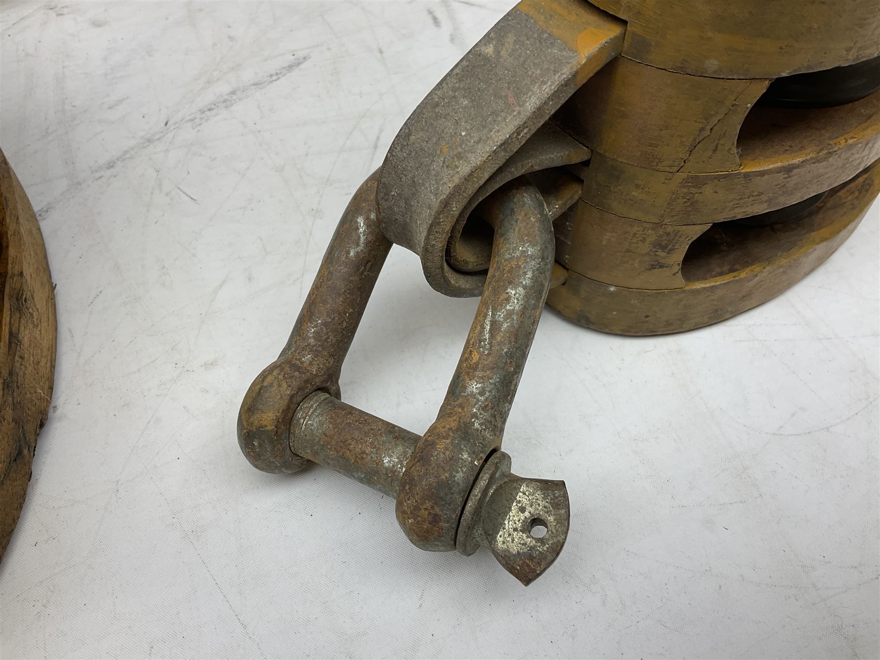 Three ship pulleys comprising wooden block double with swivel eye marked 'wooden block 240mm double rope: 22mm',  wooden block double with upset shackle and wooden block with stiff swivel hook, largest example L50cm