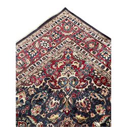 Persian Kashan indigo ground carpet, large central rosette medallion decorated with alternating palmettes, the surrounding field and spandrels with overall floral design depicting trailing branches and stylised plant motifs, crimson ground border with trailing floral pattern, enclosed within guard stripes 