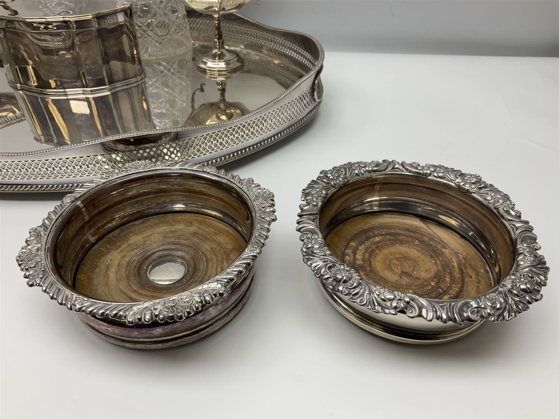 Pair of Mappin and Webb silver plate pierced pedestal bon bon dishes, together with other silver plate comprising teapot stand engraved with lion's head to centre, two cut glass claret jugs, two bottle coasters with acorn decoration, two open salts upon dolphin mounts, tea caddy, three piece cruet set and a large oval tray with pierced sides and upon four ball feet