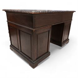 Victorian carved oak twin pedestal desk, moulded and foliate carved rectangular top with leather inset, fitted with nine drawers, each carved with scrolling foliage and lion mask handles, on skirted base 