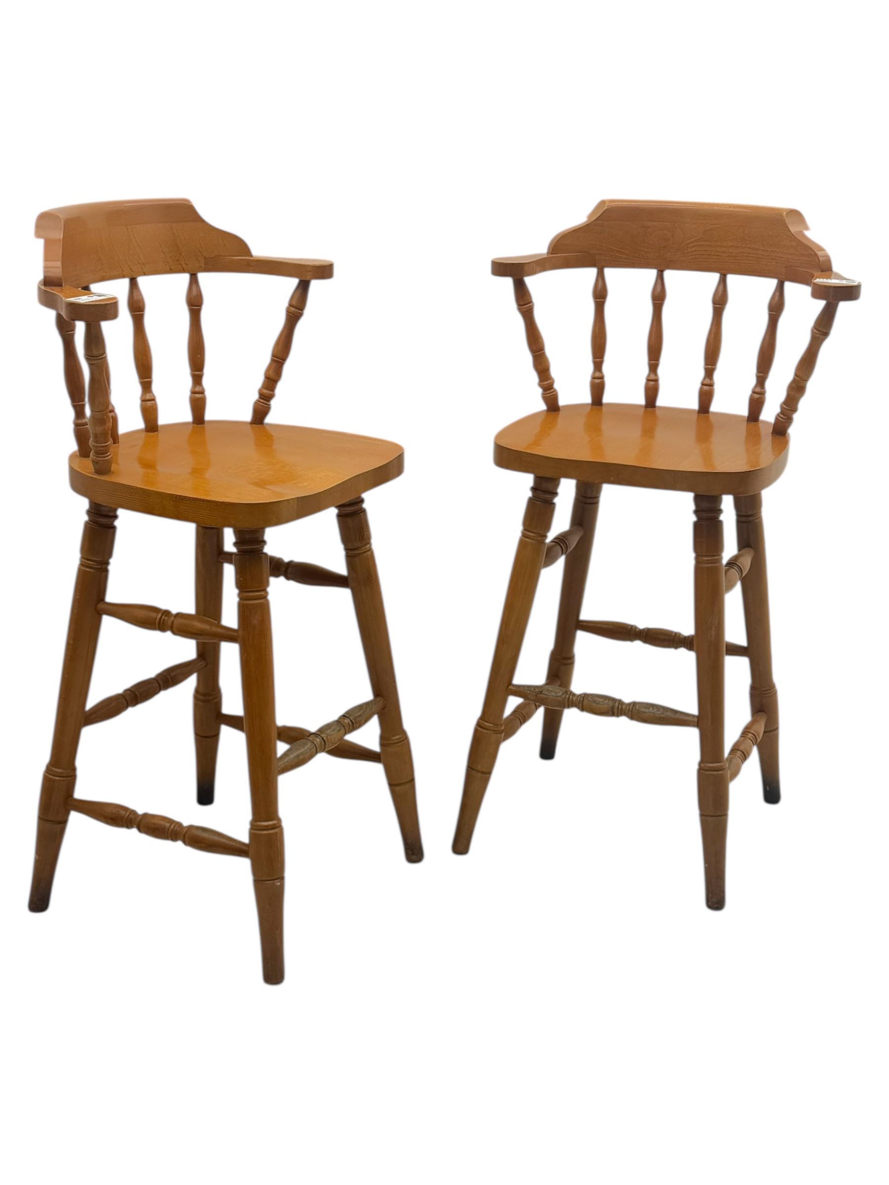 Pair of late 20th century beech bar stools, with curved top rail and turned spindle back, shaped seat over four turned legs united by multiple stretchers