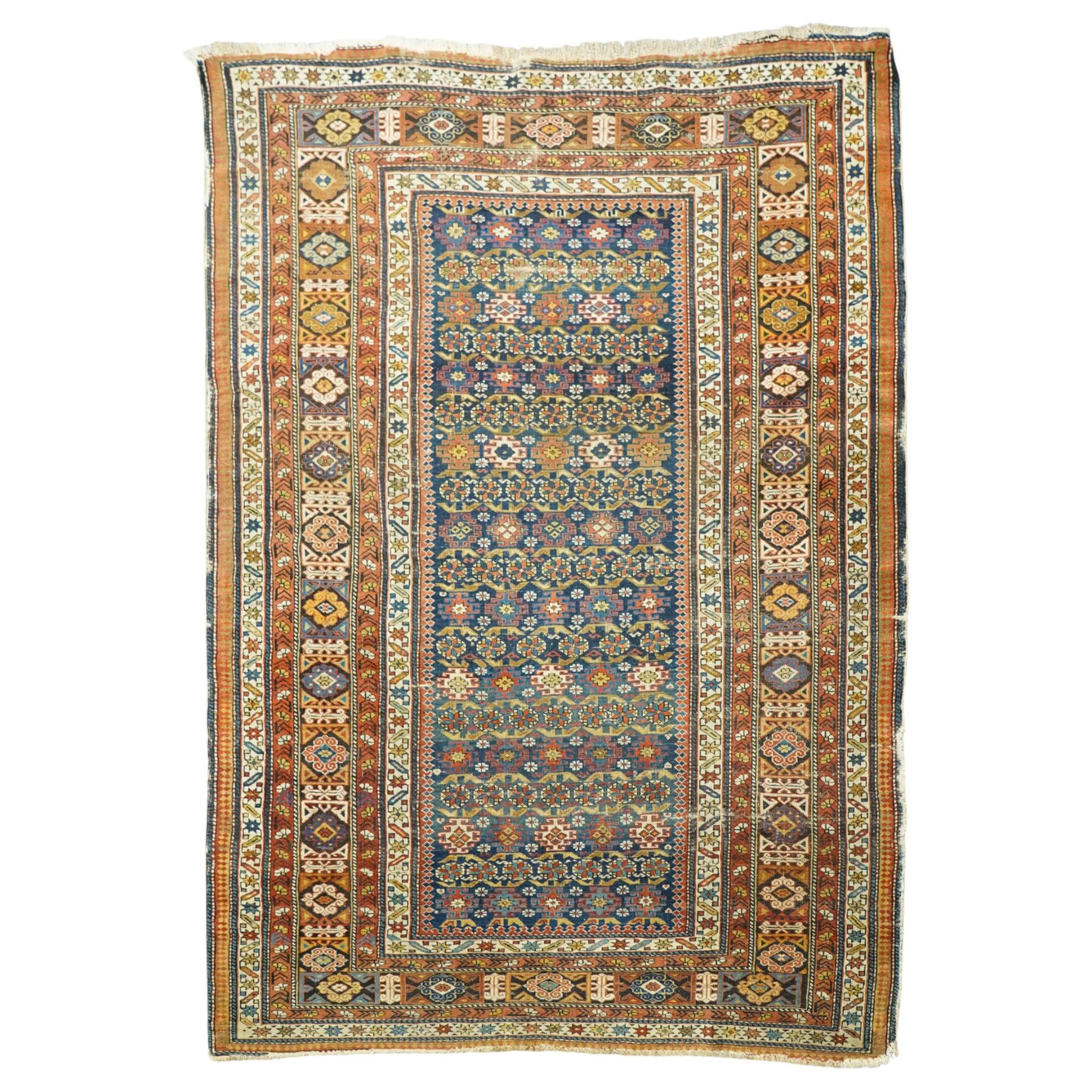 Two antique Caucasian Shirvan rugs, indigo field decorated with horizontal bands of small geometric floral and star motifs within multiple finely drawn borders featuring diamonds, rosettes, and stylized leaves in a palette of madder red, ivory, ochre, and pale blue, with fringe ends, 195x137cm, together with a similar smaller rug, 143x96cm
