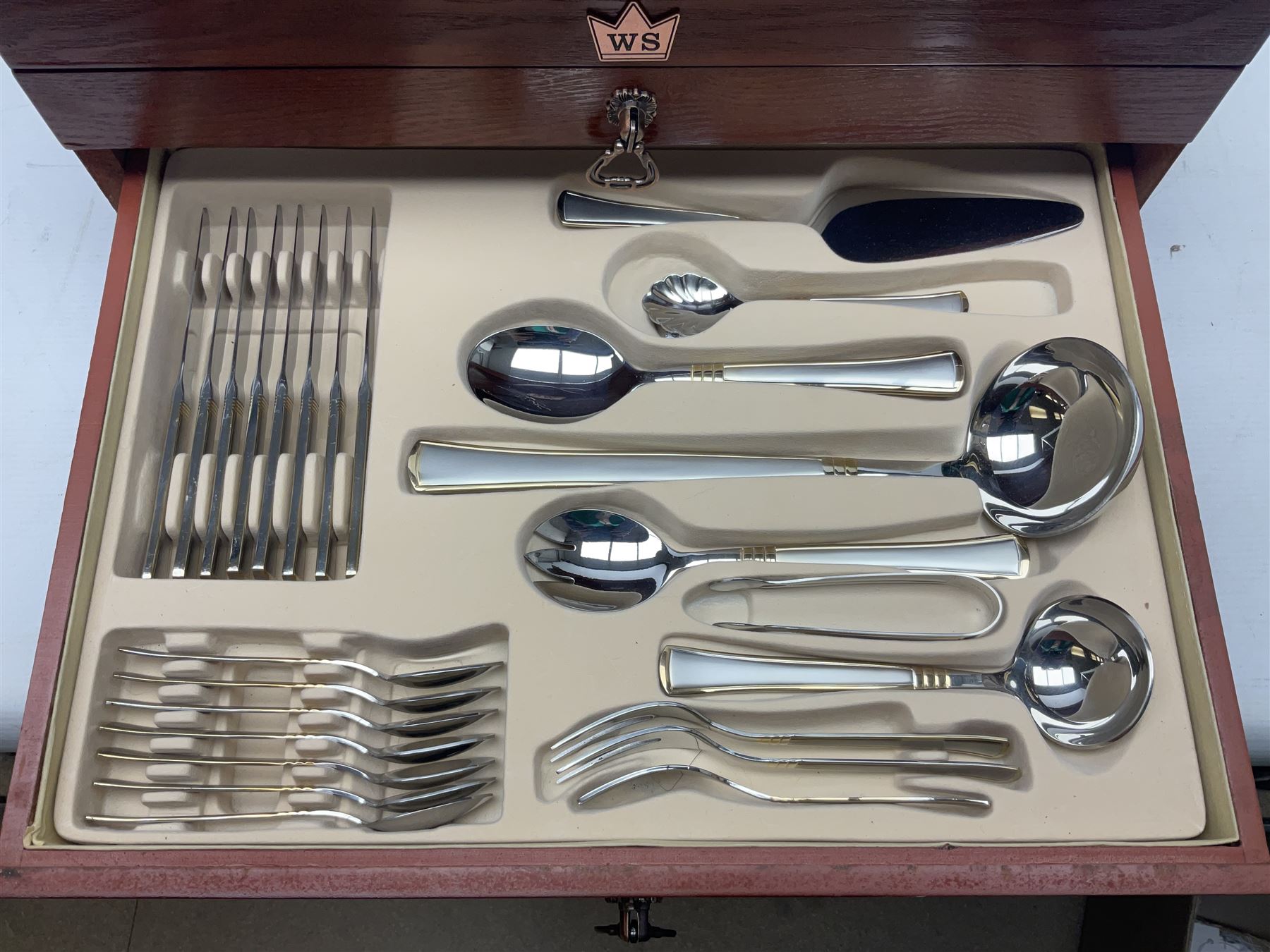 Waltmann und Sohn part canteen of stainless steel and gilt cutlery, the stained wood case with hinged lid above two fitted drawers, L48cm