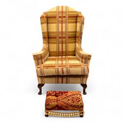 20th century Georgian style upholstered wingback armchair with footstool, the chair in yellow and red plaid fabric, the stool with fringed tapestry cover