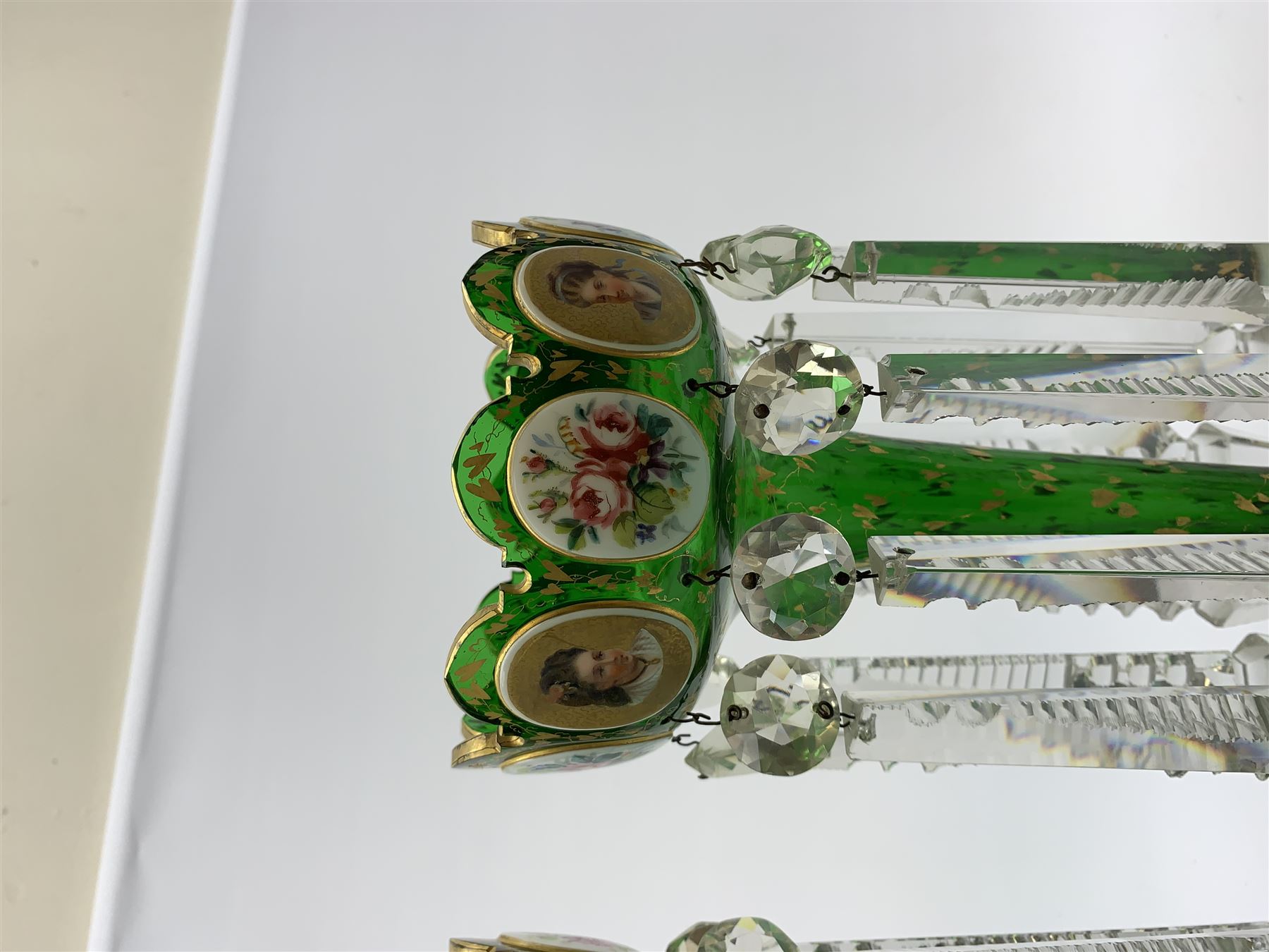 Pair of 19th century Bohemian green glass lustres, the castellated bowls decorated with overlaid panels of flowers and female portraits, upon tapering stems and overlaid spreading feet, heightened throughout with gilt, each supporting ten prismatic drops, H35cm