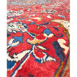 Northwestern Persian Lillihan hand-knotted carpet, madder red field with scrolling vines, rosettes, and palmettes around a central circular medallion in navy, ivory and ochre, and ivory ground spandrels within a navy border of stylized flowerheads and vines between multiple guard stripes 