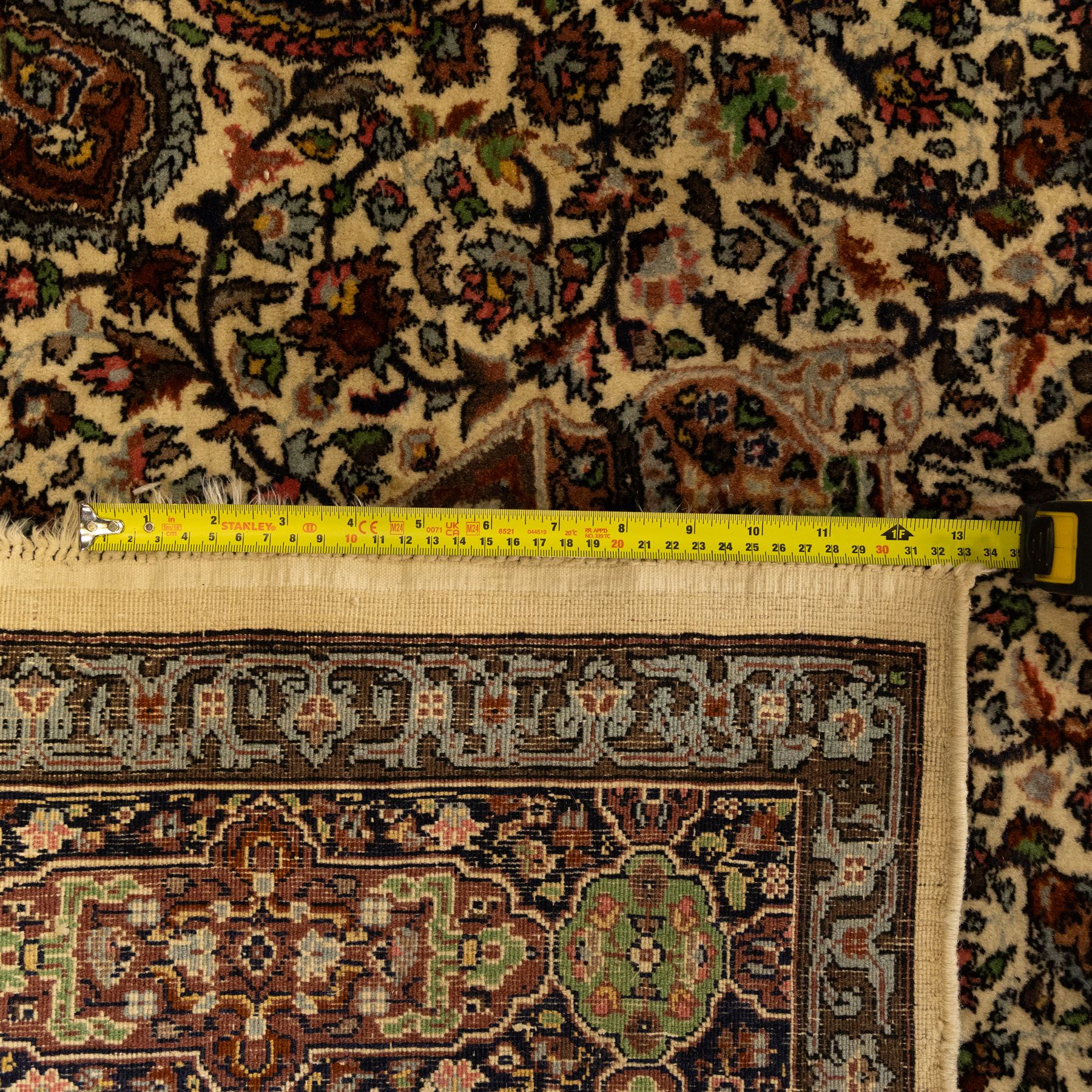 Persian Nain hand-knotted rug, central circular medallion with radiating floral scrolls and palmettes enclosed by ivory field with boteh and foliate motifs, framed by a series of guard stripes and a main border with scrolling arabesques in a midnight blue ground 