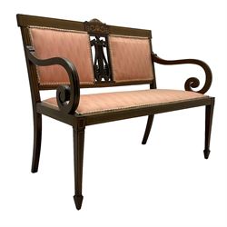 Edwardian inlaid mahogany two-seat settee or hall bench, the cresting rail inlaid with satinwood banding and boxwood stringing, central panel inlaid with scrolled leafy branches over pierced and carved lyre back, upholstered in peach fabric with repeating pattern, scrolled down sweeping arms, on square tapering supports with spade feet 