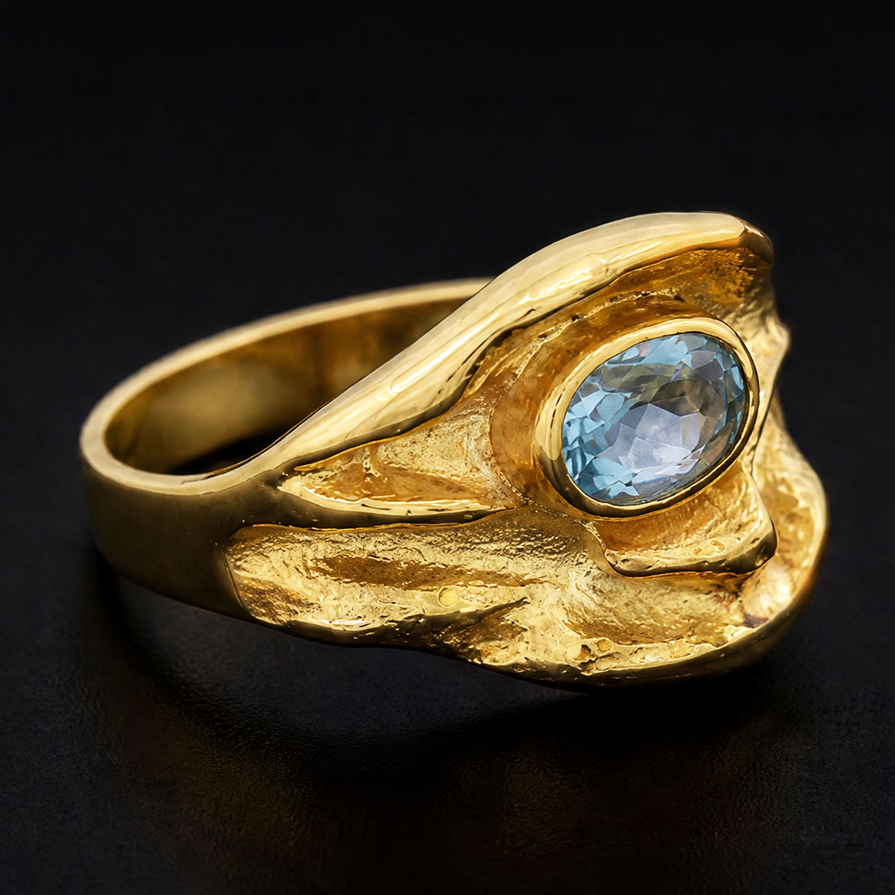 18ct gold Swiss blue topaz ring, bezel single oval cut topaz, within an abstract creased design setting, stamped 750