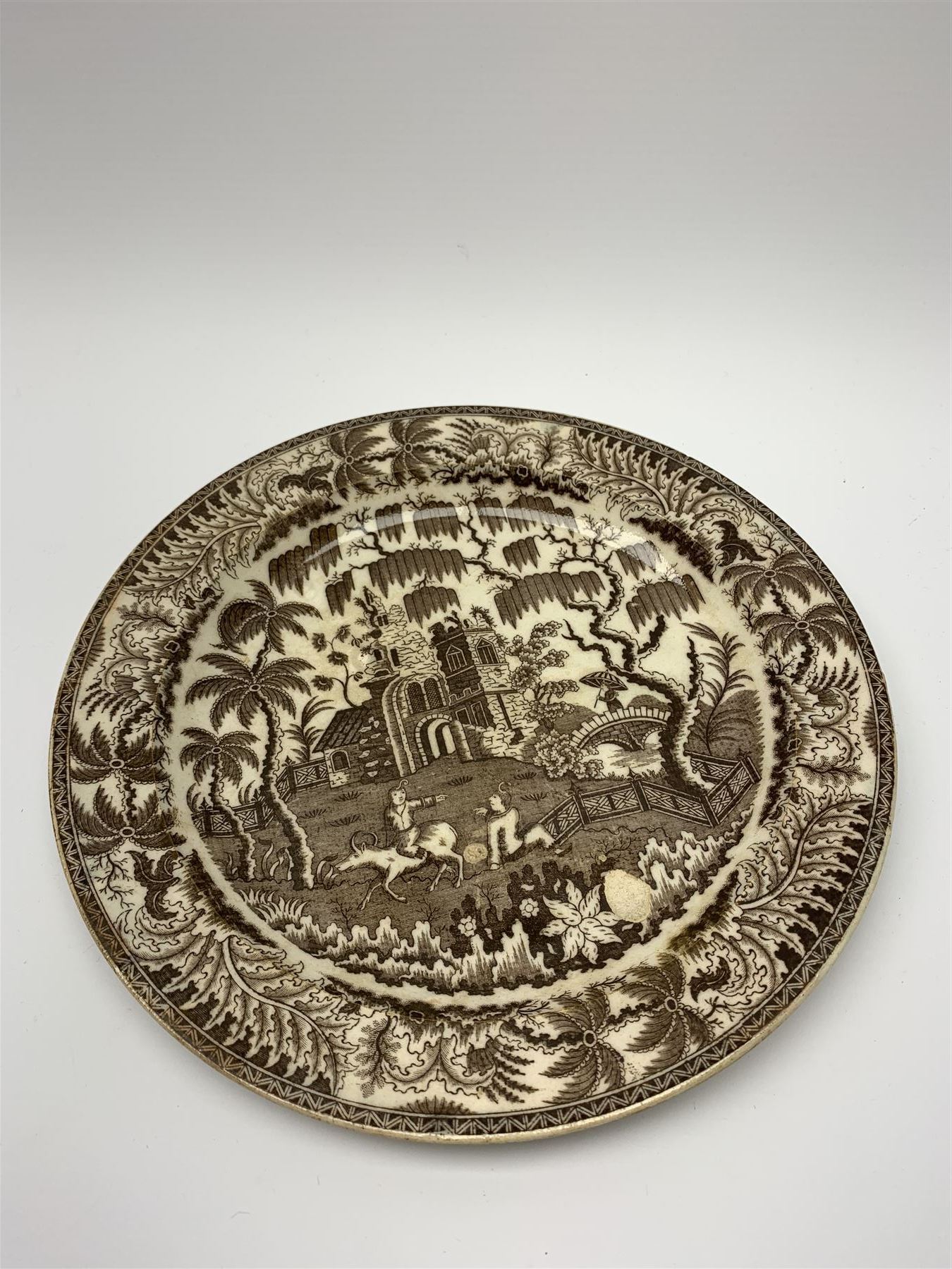 Early 19th century David Dunderdale & Co Castleford pottery plate, decorated in brown in the Buffalo and Ruins pattern, with indistinct impressed marks beneath, D24cm, together with a late 18th/early 19th century blue and white pearlware sauce boat, decorated in a variant of the Willow pattern, L15cm