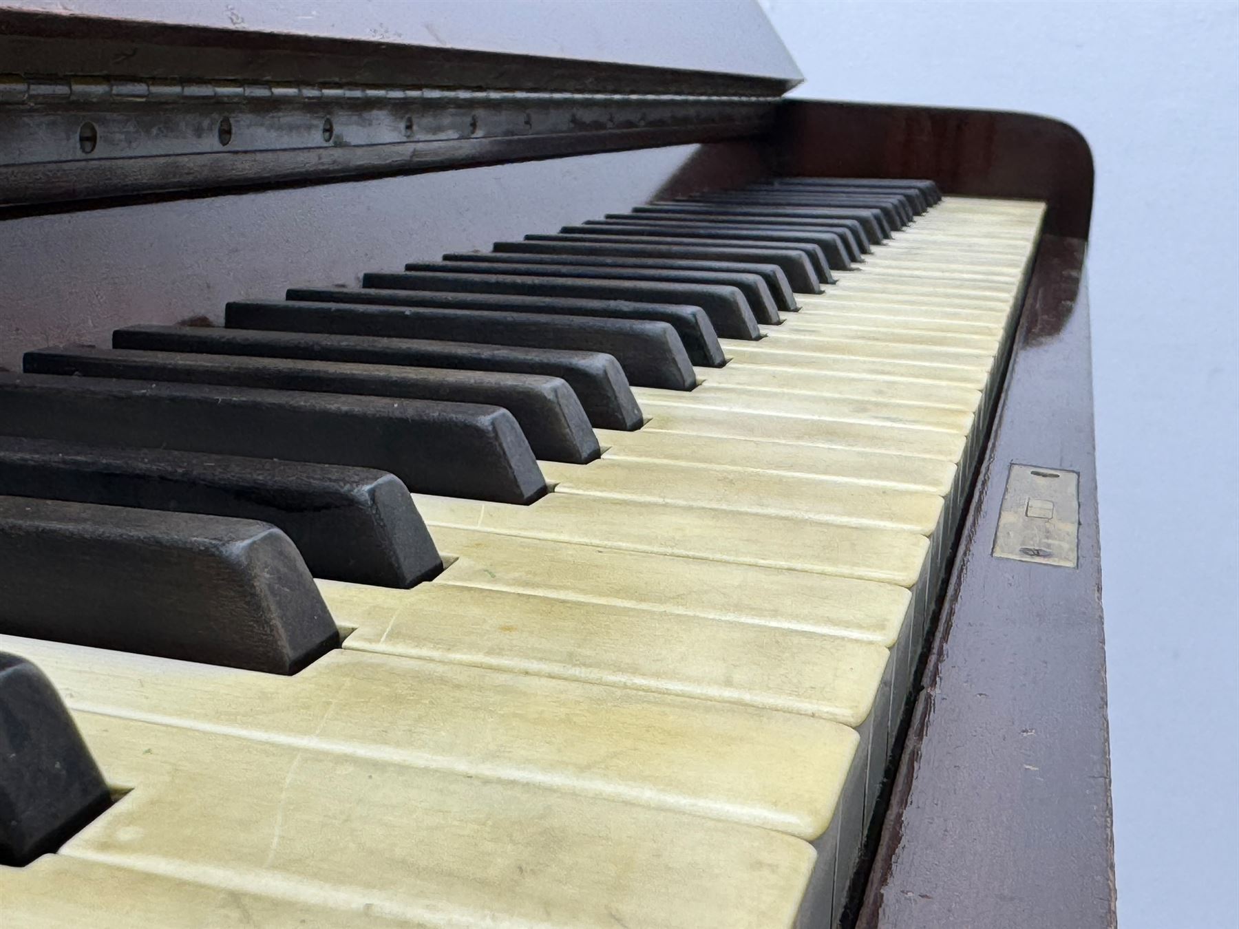 Waddington - Edwardian mahogany upright piano, rectangular top with panelled front, rounded key cover, makers name on fallboard, raised on bracket supports with castors
