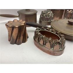 Four Victorian copper moulds, together with a graduating set of copper pans with wooden handles and finials to covers, largest pan 