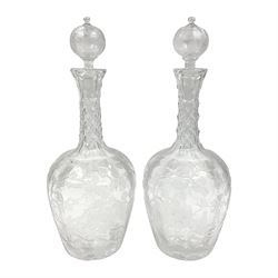 Pair of early 20th century cut glass decanters, each of ovoid form, the bodies deeply cut and etched with fruiting vines, the diamond cut necks supporting globular stoppers with conforming cut and etched decoration, H28cm