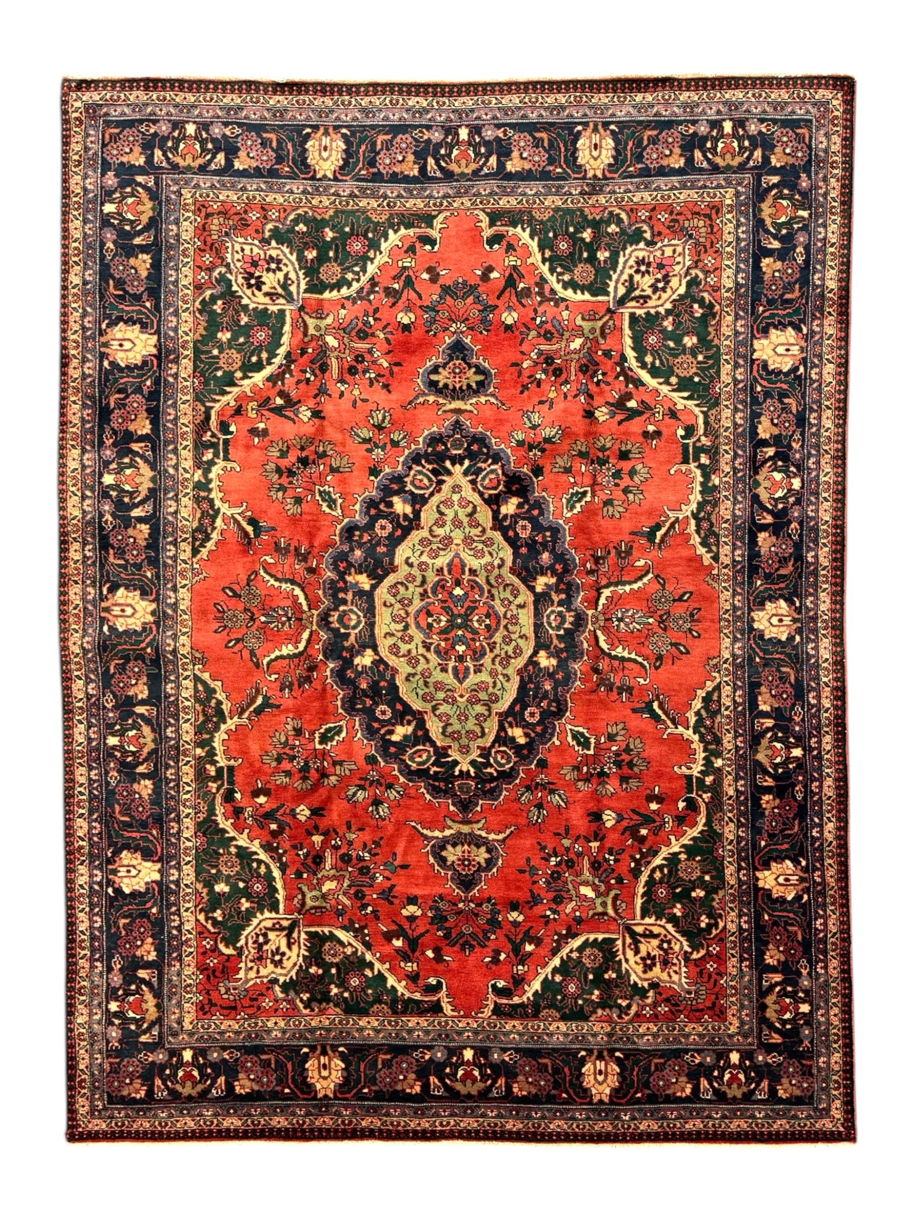 North East Persian Meshed crimson ground carpet, central indigo and green medallion with floral decoration, busy field with trailing foliage and stylised flowers, matching spandrels with floral motifs, indigo border featuring scrolling vines and palmettes, framed by narrow floral guard bands