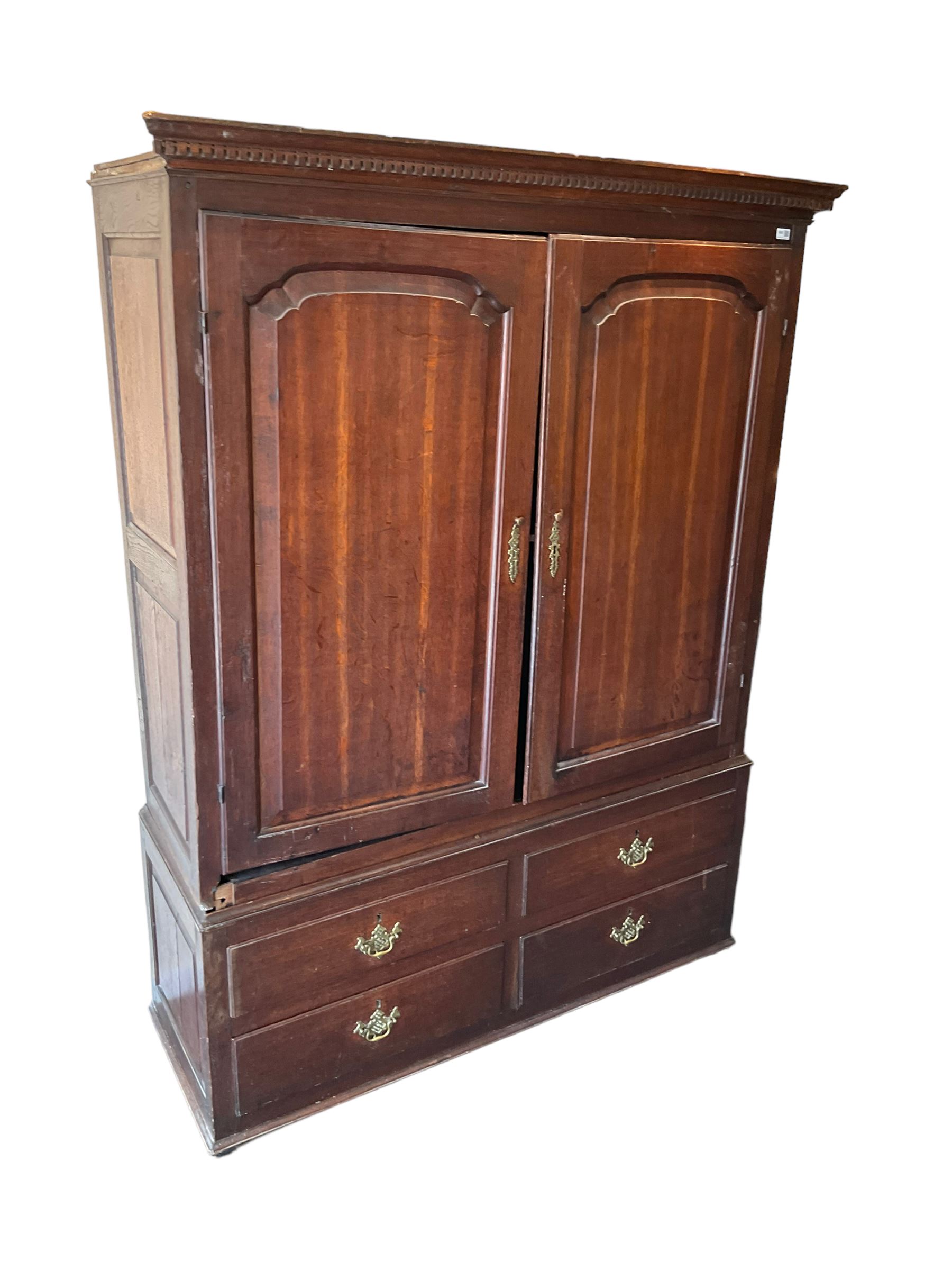 George III oak press cupboard, dentil cornice over two arch fielded panel doors, the base fitted with four drawers with pressed brass handle plates