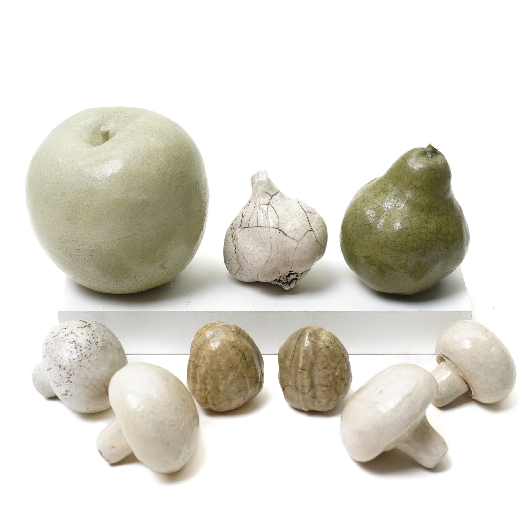 Collection of ceramic fruit and vegetables, including raku examples, comprising two walnuts, three mushrooms, one garlic bulb, a pear and an apple