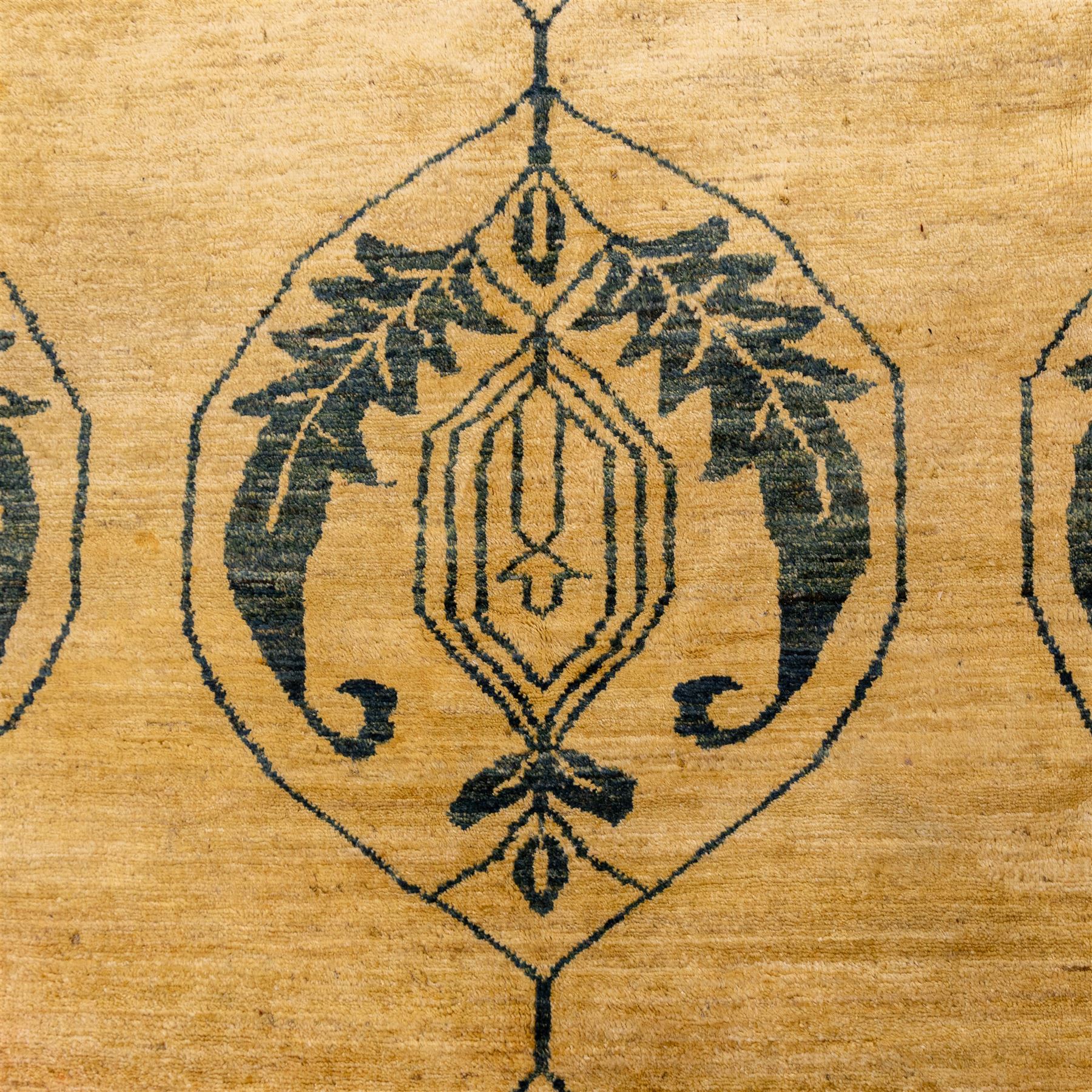 Late 20th century Turkish hand-woven carpet, golden beige field decorated with a repeating lattice of stylized medallions enclosing boteh and angular foliate motifs linked by issuing scrolling vinery within a border of complementary stylized leaf scrolls