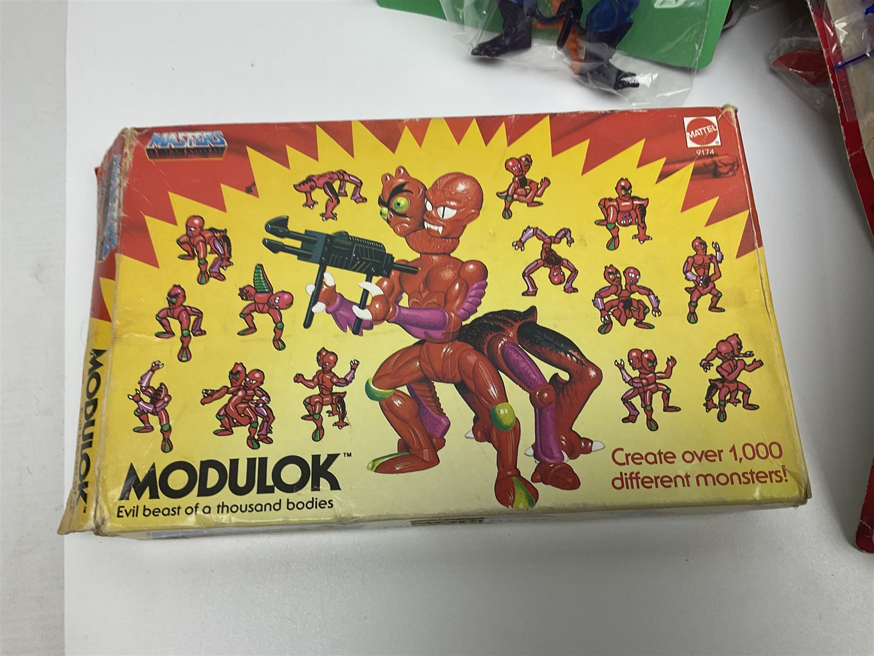 Thirty-one Masters of the Universe He-Man figures re-bagged on original backing cards;  two others lacking backing cards; boxed Modulok figure; bag of weapons and accessories; Roton, two horses and two battle cats; 1986 & 1987 Annuals; Ladybird and other story books; Panini sticker album; instructions etc