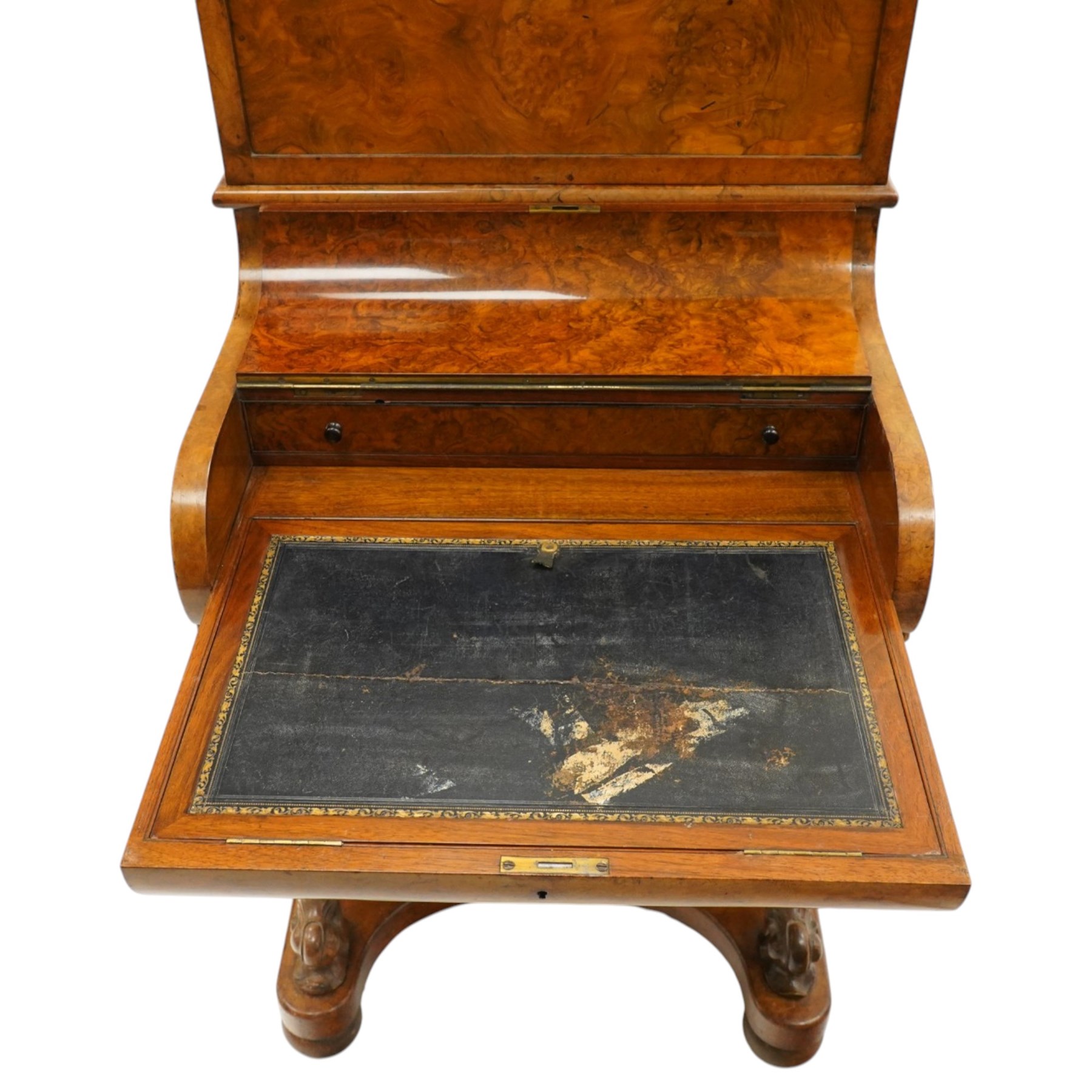 Victorian burr walnut piano-top Davenport, the raised rectangular superstructure with moulded cornice above a panelled fall-front enclosing drawers, the curved hinged writing slope opening to reveal a fitted interior above a sliding tooled leather writing surface, flanked by carved foliate scroll supports, the right side fitted with four drawers behind an arched panelled cupboard door with brass inset campaign-style handles, on a shaped plinth base and bun feet