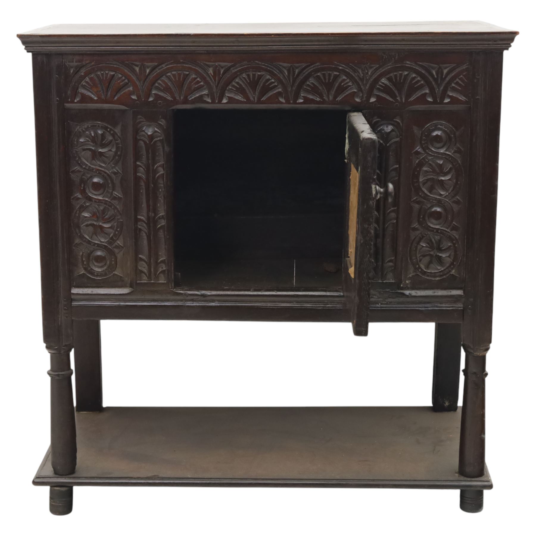 19th century oak cupboard cabinet, the moulded rectangular top above a deeply carved front carved with frieze of lunettes above a central panelled cupboard door with lozenge and foliate carving, flanked by vertical carved panels, upon turned legs with boarded lower shelf