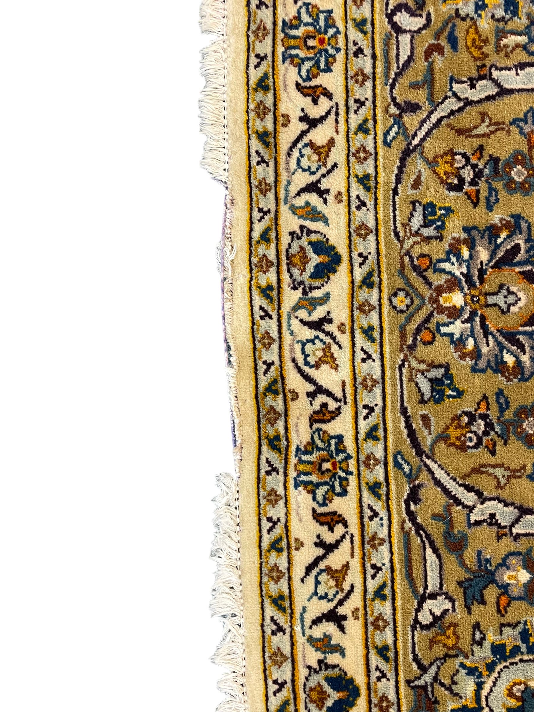 Persian Kashan ivory ground carpet, the field decorated with trailing foliate branches and stylised flower head motifs, guarded border with repeating design decorated with scrolling leafy branch and plant motifs 