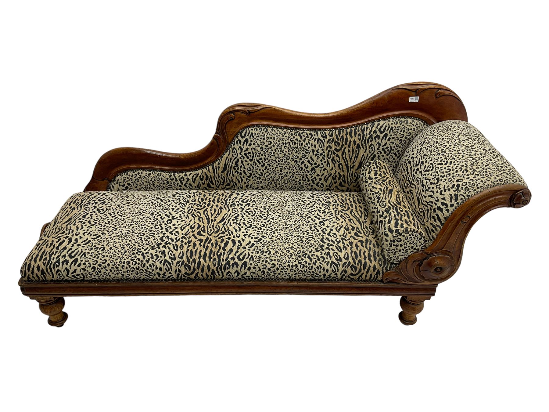 Victorian mahogany framed chaise longue, shaped arm carved with acanthus leaves, the scrolled back with applied carved rosettes,upholstered in monochrome leopard print fabric with bolster cushion, raised on turned supports