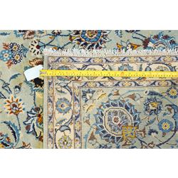 Central Persian Kashan hand-knotted carpet, pale blue field decorated with an all-over scrolling floral vine design incorporating stylized palmettes, rosettes and foliate sprays enclosed by a conforming floral vine border between multiple guard stripes, with cotton fringe ends 