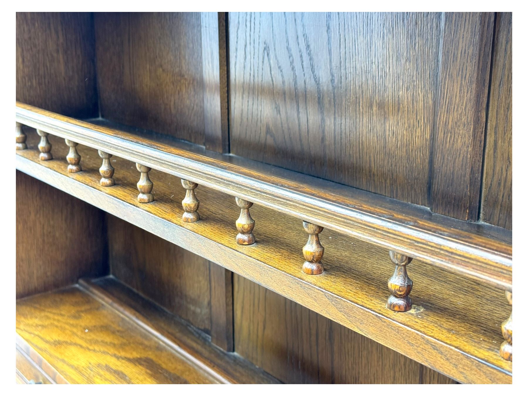 Large mid-20th-century oak dresser with two astragal glazed doors between gallery shelf and lower shelf, with three short drawers and lower section with four drawers and three double-panelled linen-fold hinged cupboard doors 