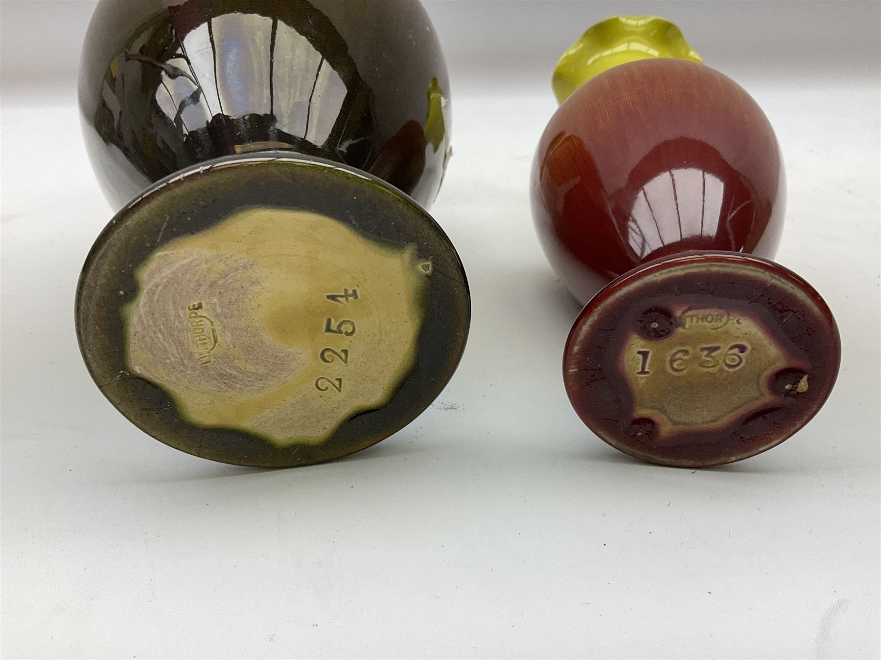 Linthorpe pottery vase with crimped rim and ovoid body, Linthorpe jug with high loop handle and crimped spout, a pair of candlesticks with a green, brown glaze and other similar pottery 