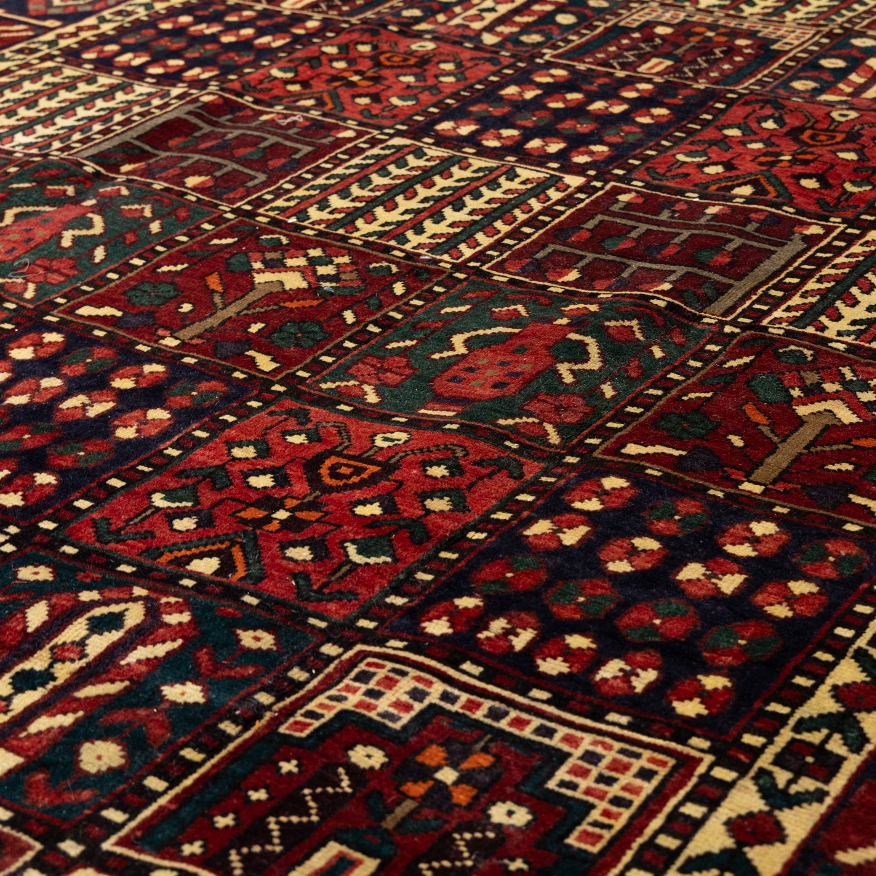 Bakhtiari wool rug, compartmented garden design field with panels of stylised trees, flowers and geometric motifs, enclosed by dark blue main border with repeating floral medallions and guard stripes