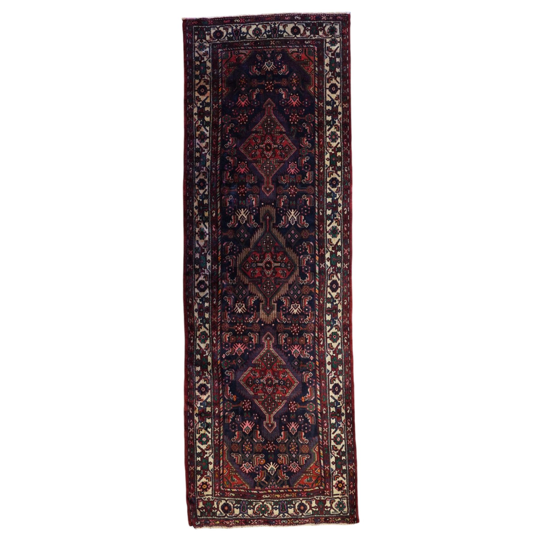 North West Persian Malayer hand-knotted runner, indigo field with vertical lozenge medallions surrounded by angular floral sprays, rosettes, and stylized palmettes, field enclosed by serrated ivory spandrels incorporating polychrome floral decoration, framed by ivory ground main border of stylized flowers and hooked devices, flanked by reciprocal guard stripes, cotton fringe ends 