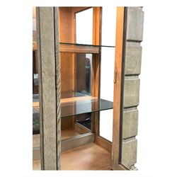 Brunswick - washed oak finish illuminated display cabinet, upper section with four glass-panelled doors enclosing glass shelving, base fitted with two drawers over four paneled cupboard doors, each fitted with distinctive round metal handles, raised on plinth base