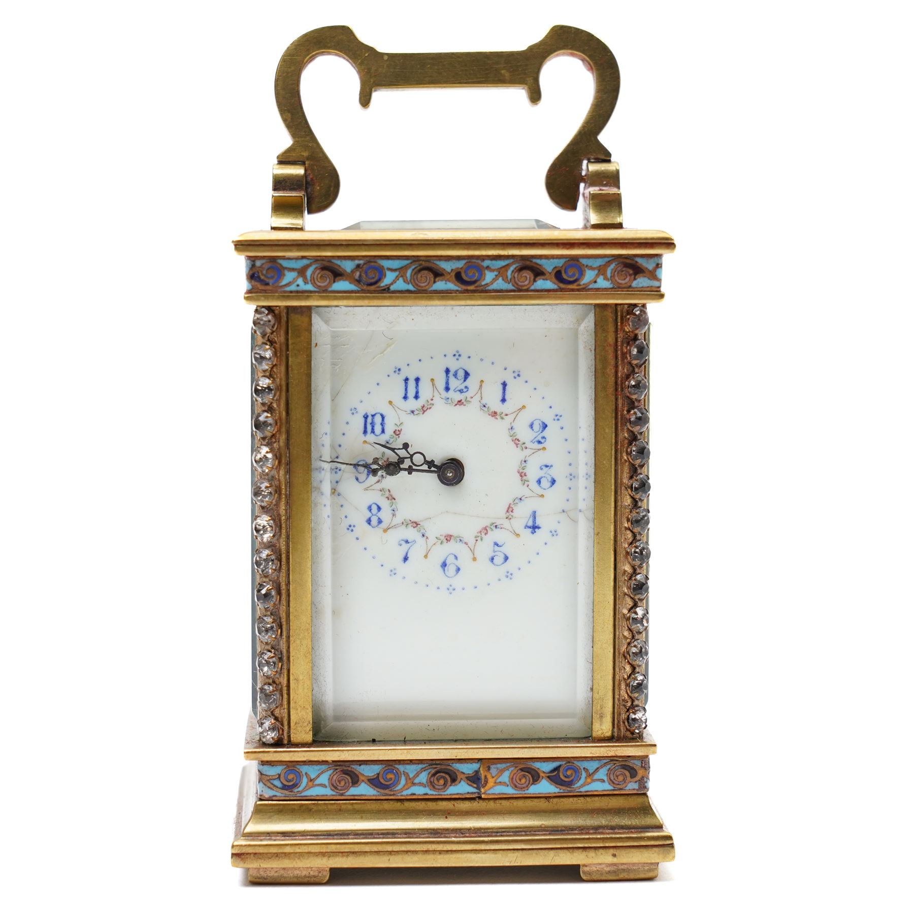 French- Edwardian miniature brass 8-day timepiece carriage clock with cloisonné panels to both base and cornice and paste gems to the front columns, decorative porcelain dial with a floral swag, blue Arabic numerals, minute track and pieced steel hands, square viewing glass to the top with a silvered lever escapement, with original leather bound traveling case.