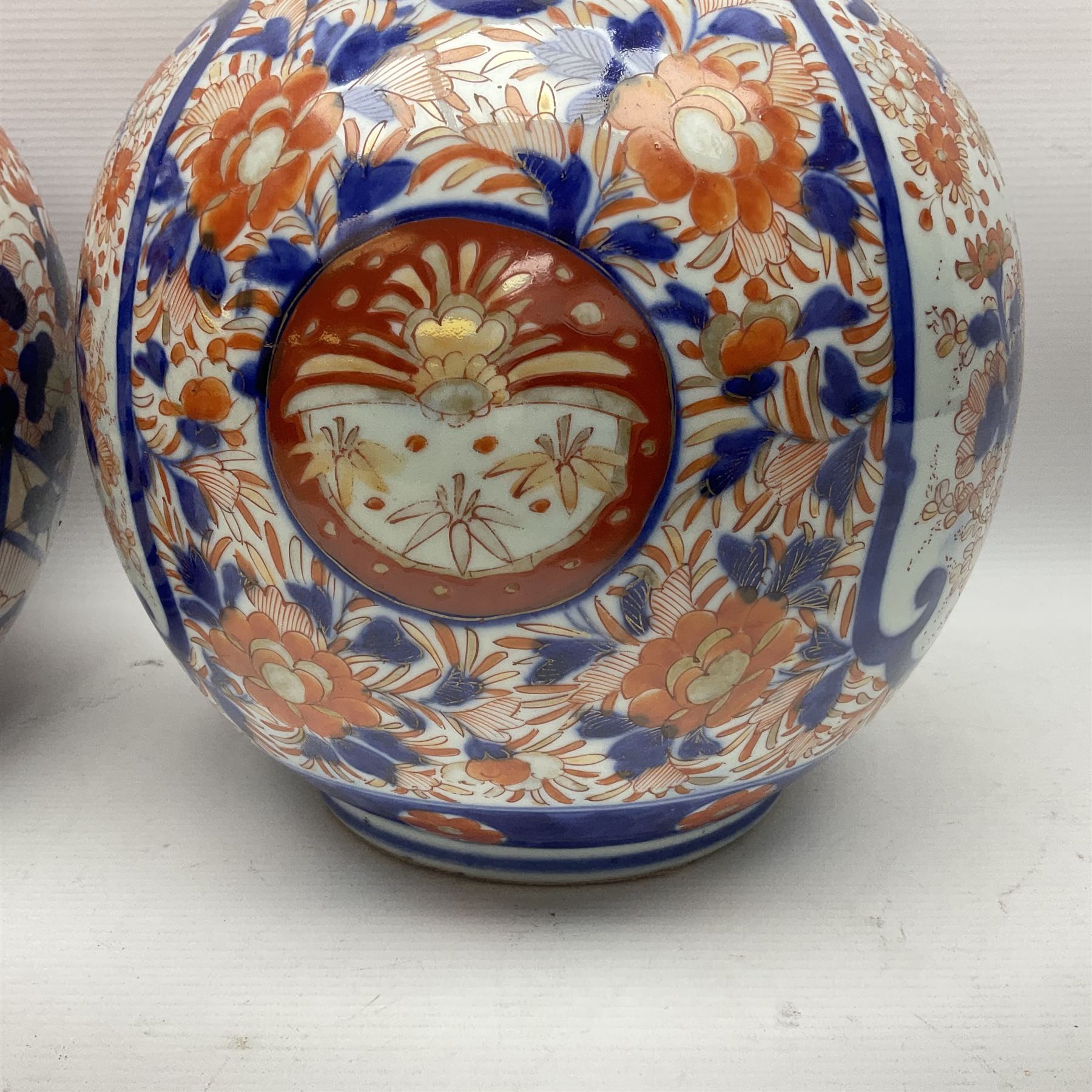 Pair of large 19th century Japanese Imari porcelain bottle vases, painted with shaped reserves of peonies, chrysanthemums and prunus blossom, each H46cm