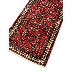 Persian red ground runner, decorated with large Herati motifs and shaped central medallion, the guarded border decorated with repeating heart motifs