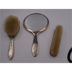 Mid 20th century silver mounted three piece dressing table set, comprising hand mirror, hair brush and clothes brush, each with white guilloche enamel decoration and set with a carved green hardstone, hallmarked Henry Clifford Davis, Birmingham 1959