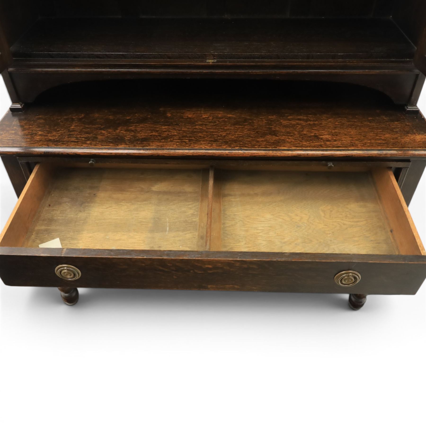Early 20th century Jacobean Revival dark stained oak dresser, the associated upper section enclosed by twin glazed doors with shaped moulded glazing bars, over separate base fitted with two drawers, raised on bobbin turned legs