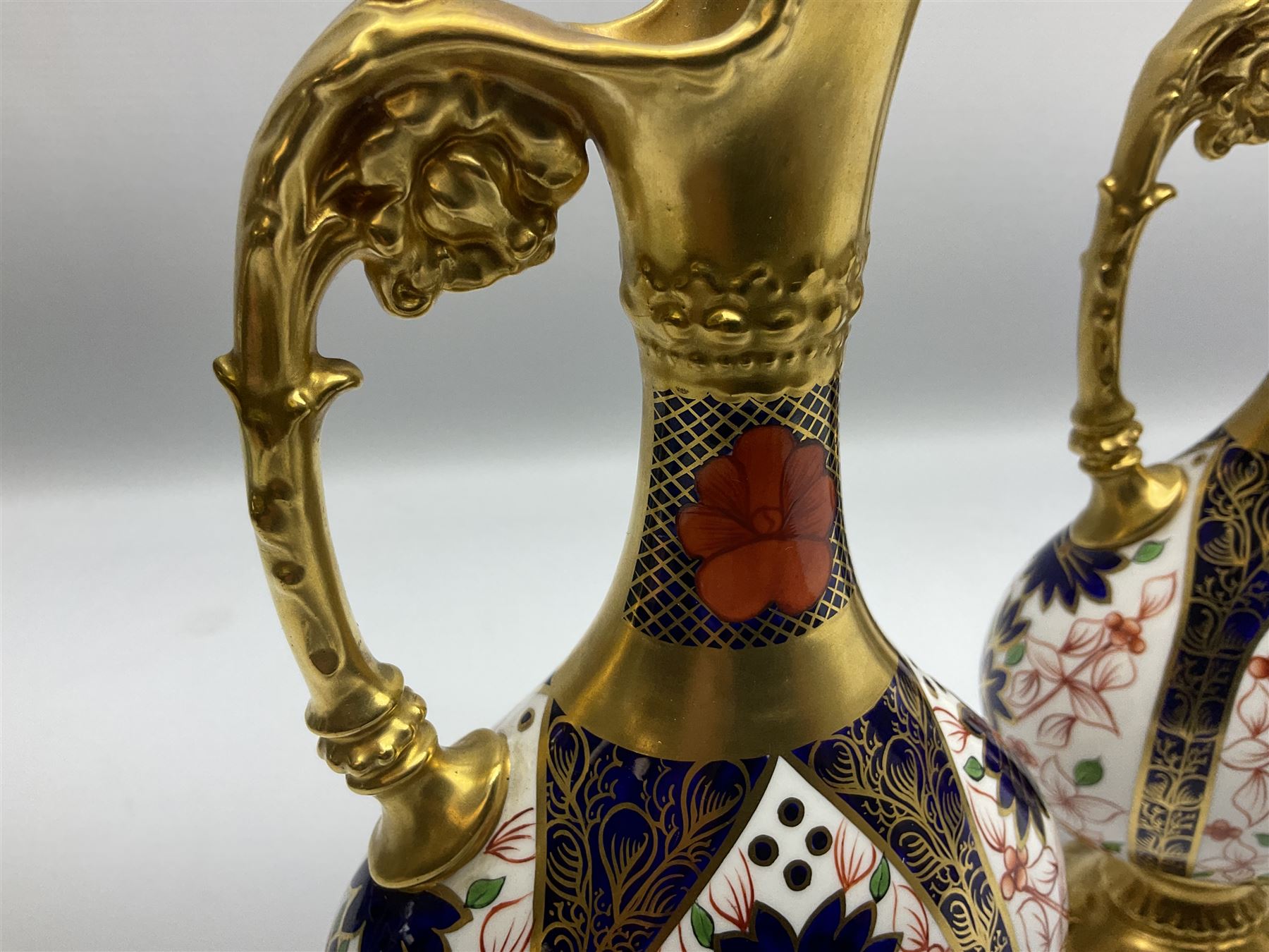 Pair of mid 20th century Royal Crown Derby Imari 1128 pattern Kedleston ewers, each with gilt scroll handle and neck, upon a gilt quatrefoil foot, each with printed marks beneath, H25.5cm