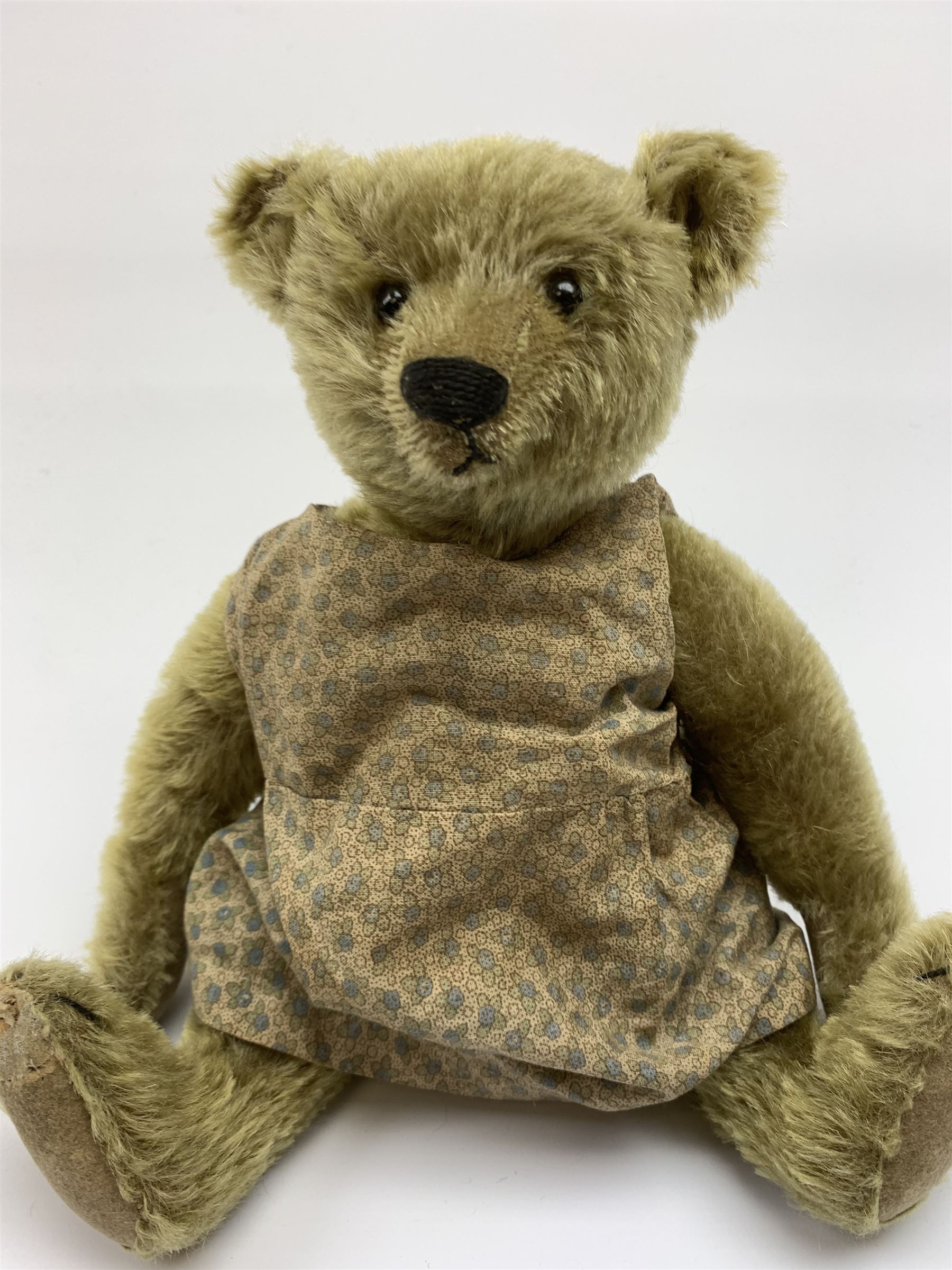 Early 20th century German Steiff teddy bear c1910 with wood wool filled humped back mohair body, swivel jointed head with black boot button eyes and horizontally stitched black nose and mouth, FF metal button to left ear, jointed elongated limbs with felt paw pads and black stitched claws H13