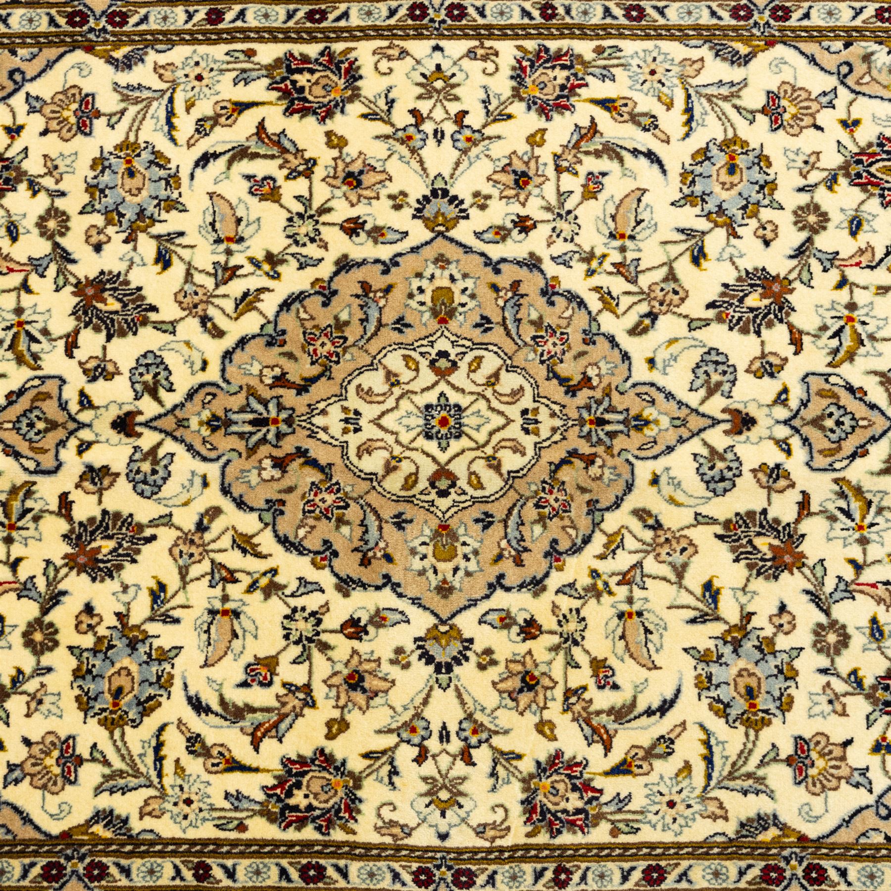 Central Persian Kashan hand-knotted rug, ivory ground, with a central shaped floral medallion with pendants, surrounded by scrolling foliate and floral motifs incorporating rosettes, palmettes and delicate vine work, enclosed by a beige border with repeating palmettes and meandering vines, flanked by narrow floral guard stripes, with cotton fringes